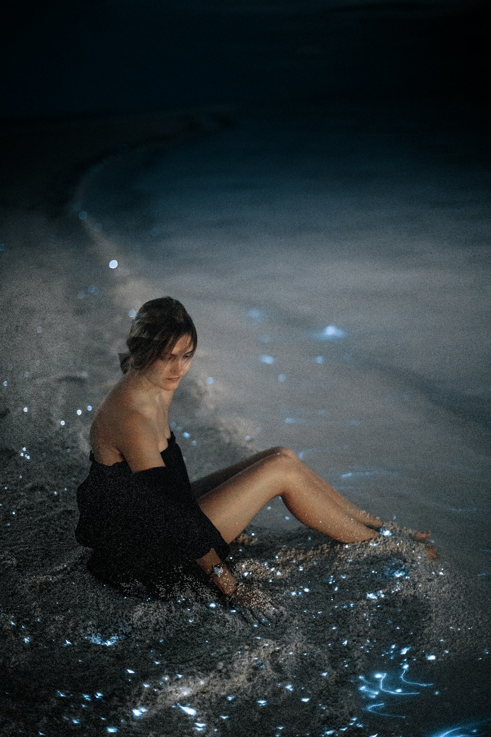 Donna seduta sulla sabbia vicino alla foto in riva al mare