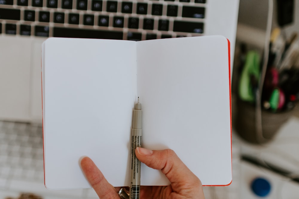 person holding book and black pen