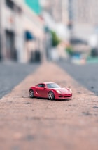 selective focus photography of red coupe scale model on road