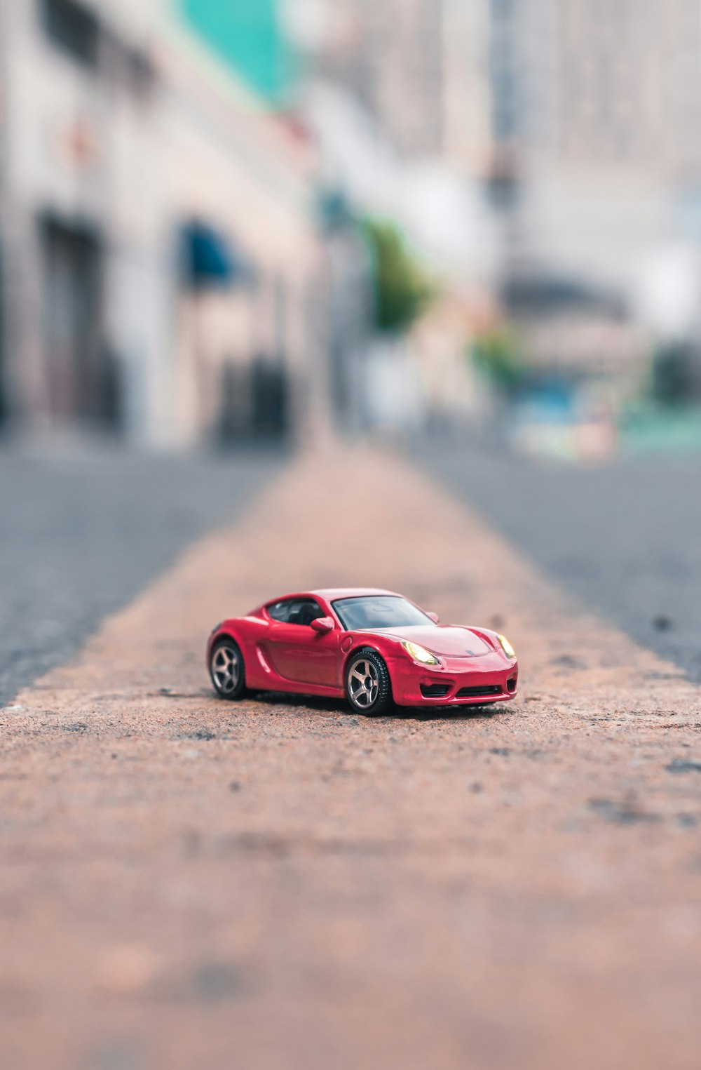 Fotografía de enfoque selectivo del modelo a escala de cupé rojo en la carretera