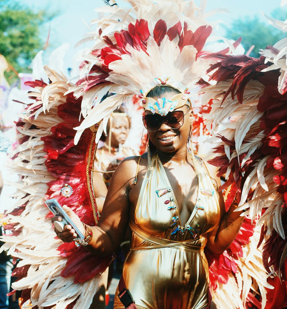 woman in gold halterneck dress walking with people wearing feather headdress