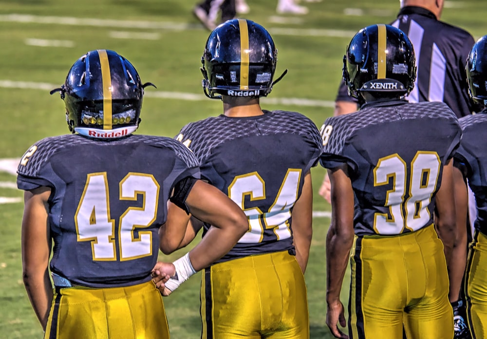 three football players standing on football field