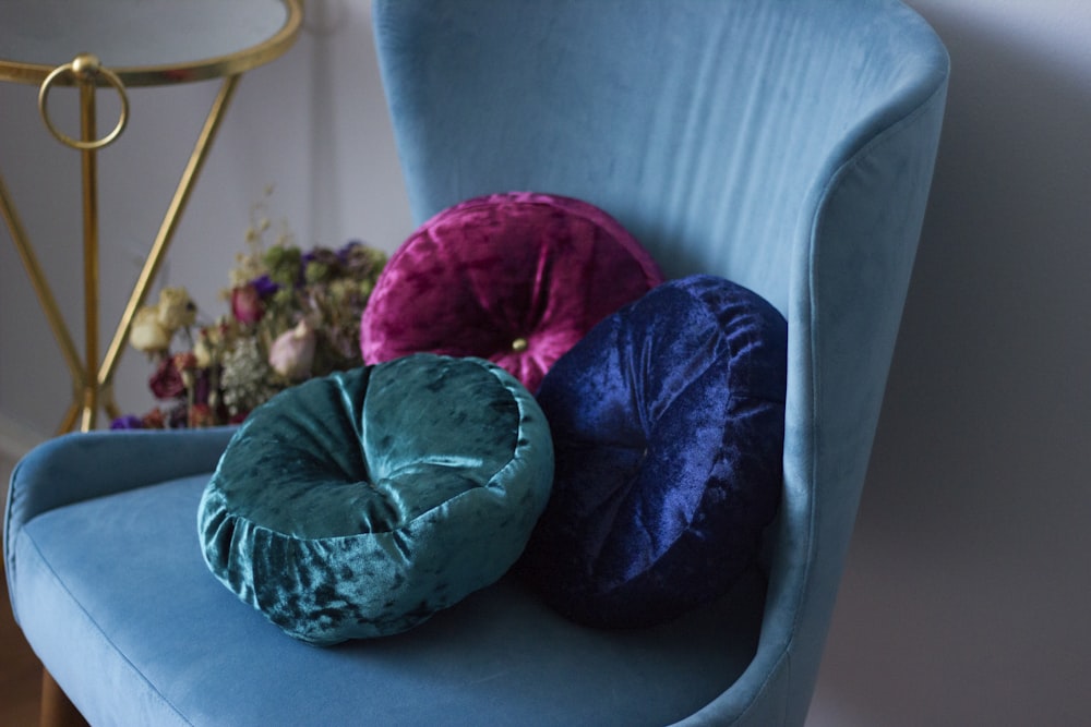 three round blue, teal, and pink velvet throw pillows on teal fabric swan chair