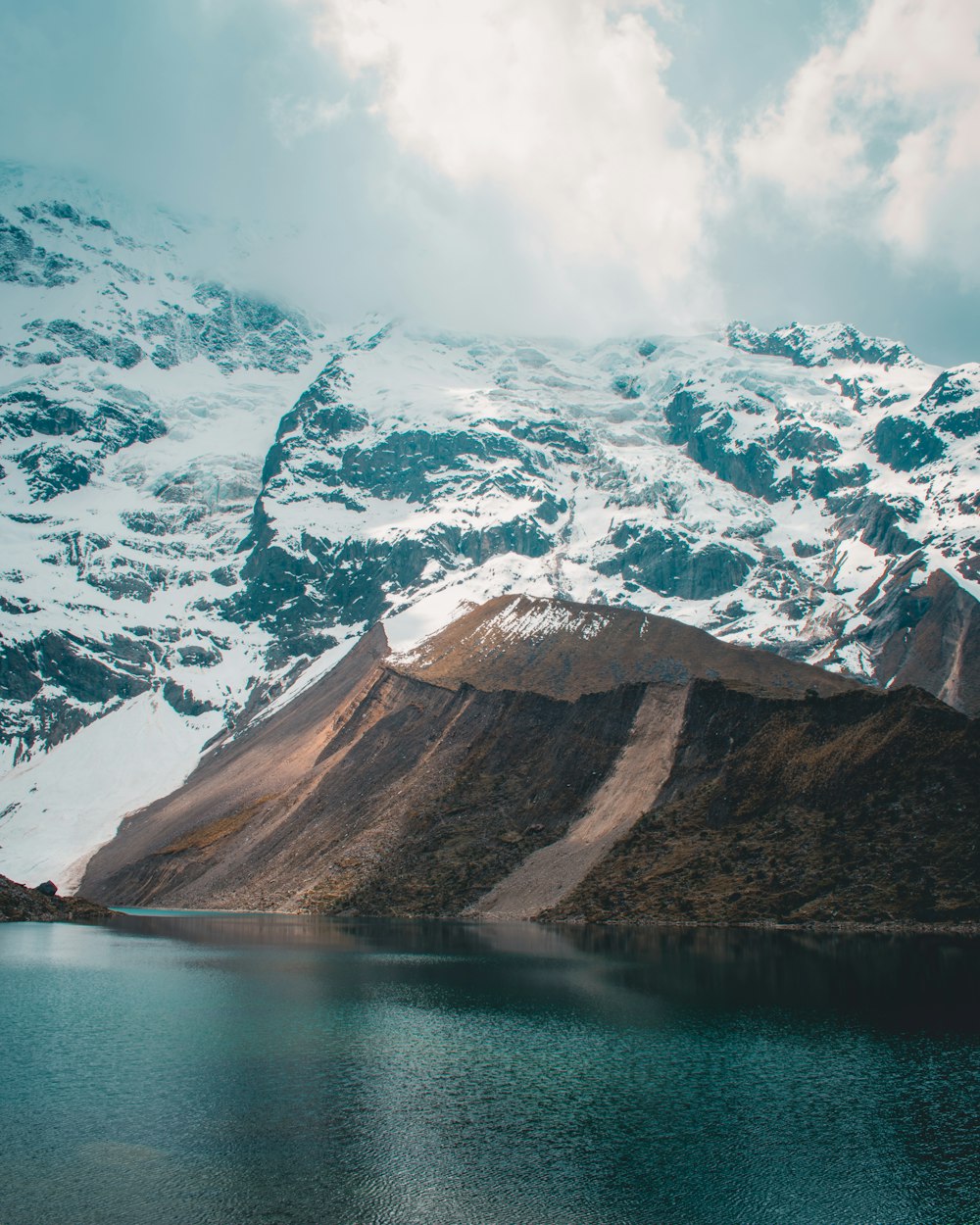 snow capped mountains near body of water at daytime