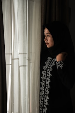 A cozy navy blue jersey hijab draped elegantly on a wooden chair by a sunlit window.