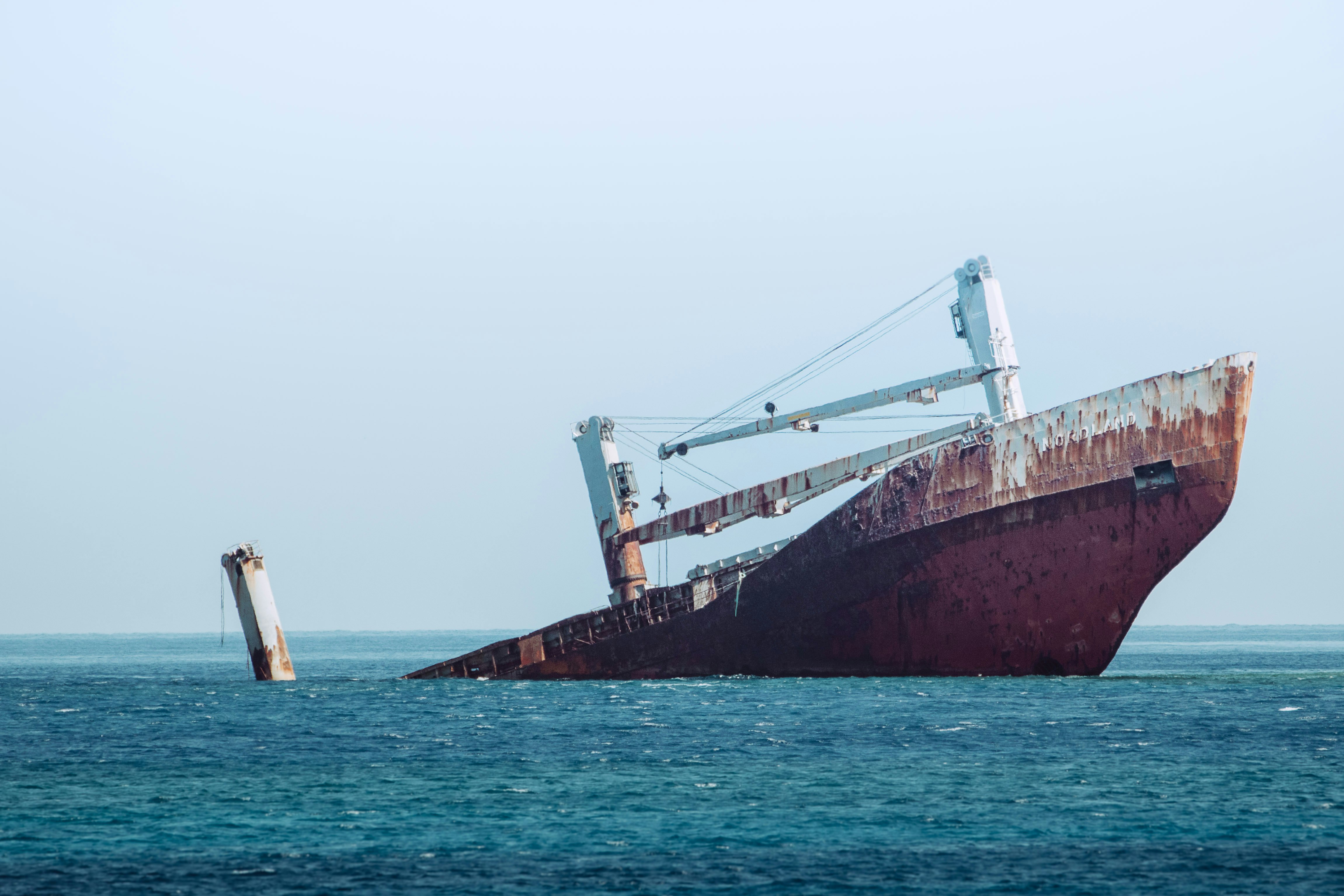 ship sinking on ocean at daytime