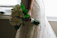 Bride holding a soft pastel bouquet with peach and nude roses in a sunlit garden.