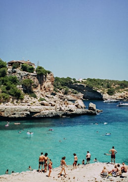 people near body of water under blue sky