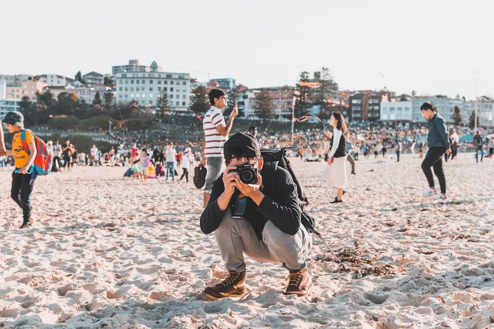 man taking photo on white sand beach