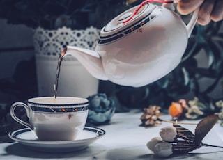 person holding white ceramic teapot