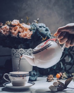 person holding white ceramic teapot