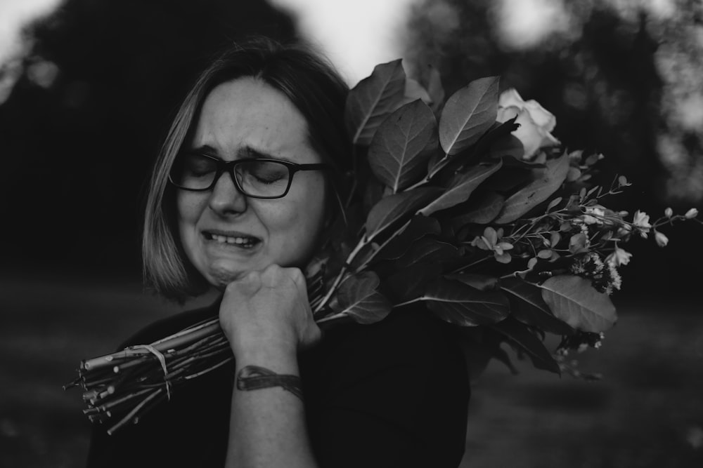 grayscale photo of crying woman holding bouquet of flowers