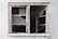 A weathered and dilapidated window with shattered glass panes against a textured, worn wall.