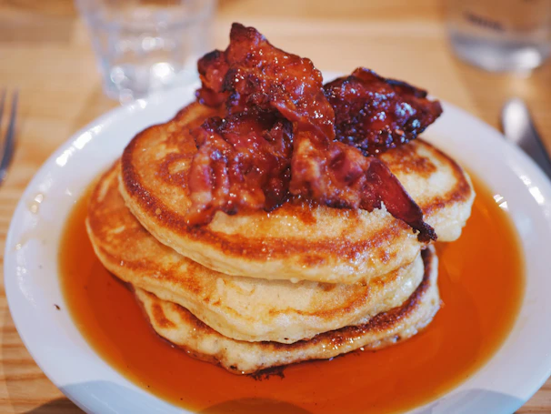 Close-up of a hearty breakfast platter featuring pancakes, eggs, and crispy bacon.