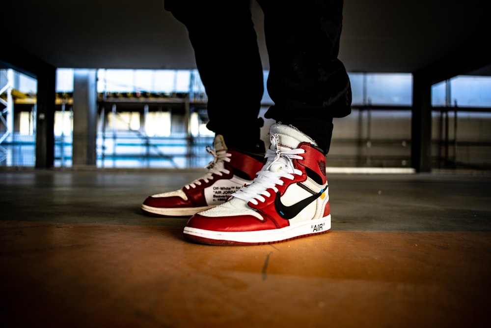pessoa vestindo branco-vermelho-e-preto Nike X Off-White Air Jordan 1