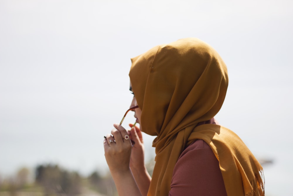 woman in brown headdress putting eyeglasses in tilt shift photography