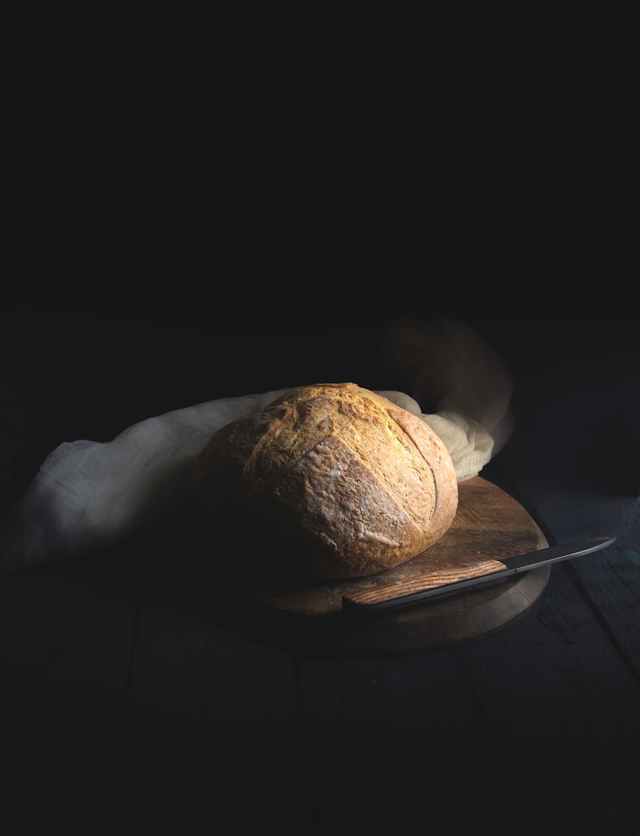 A scored sourdough loaf resting on a wooden board