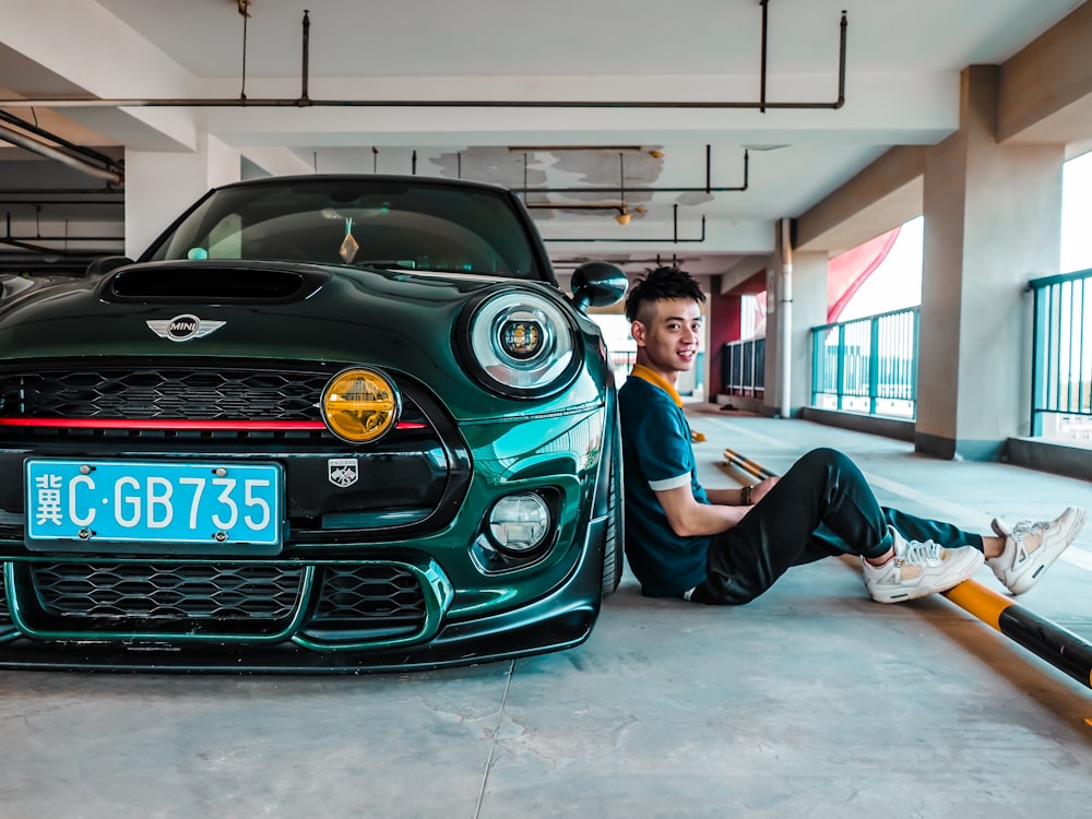 man sitting beside Mini Cooper