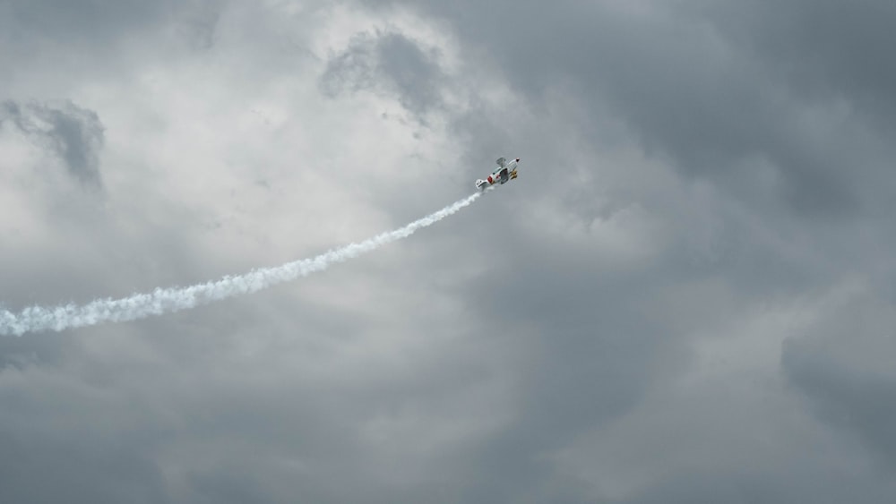 a small plane flying through a cloudy sky