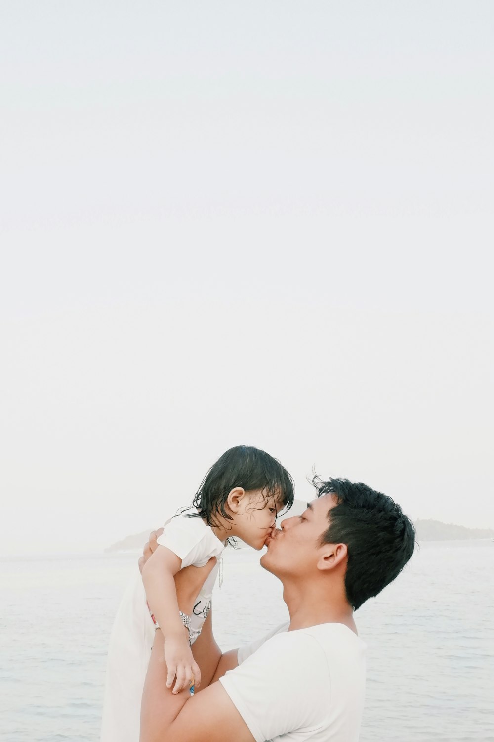 man kissing toddler during daytime