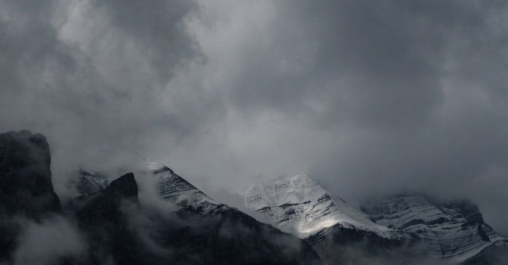 Graustufenfotografie von Bergen, die mit Nebel bedeckt sind