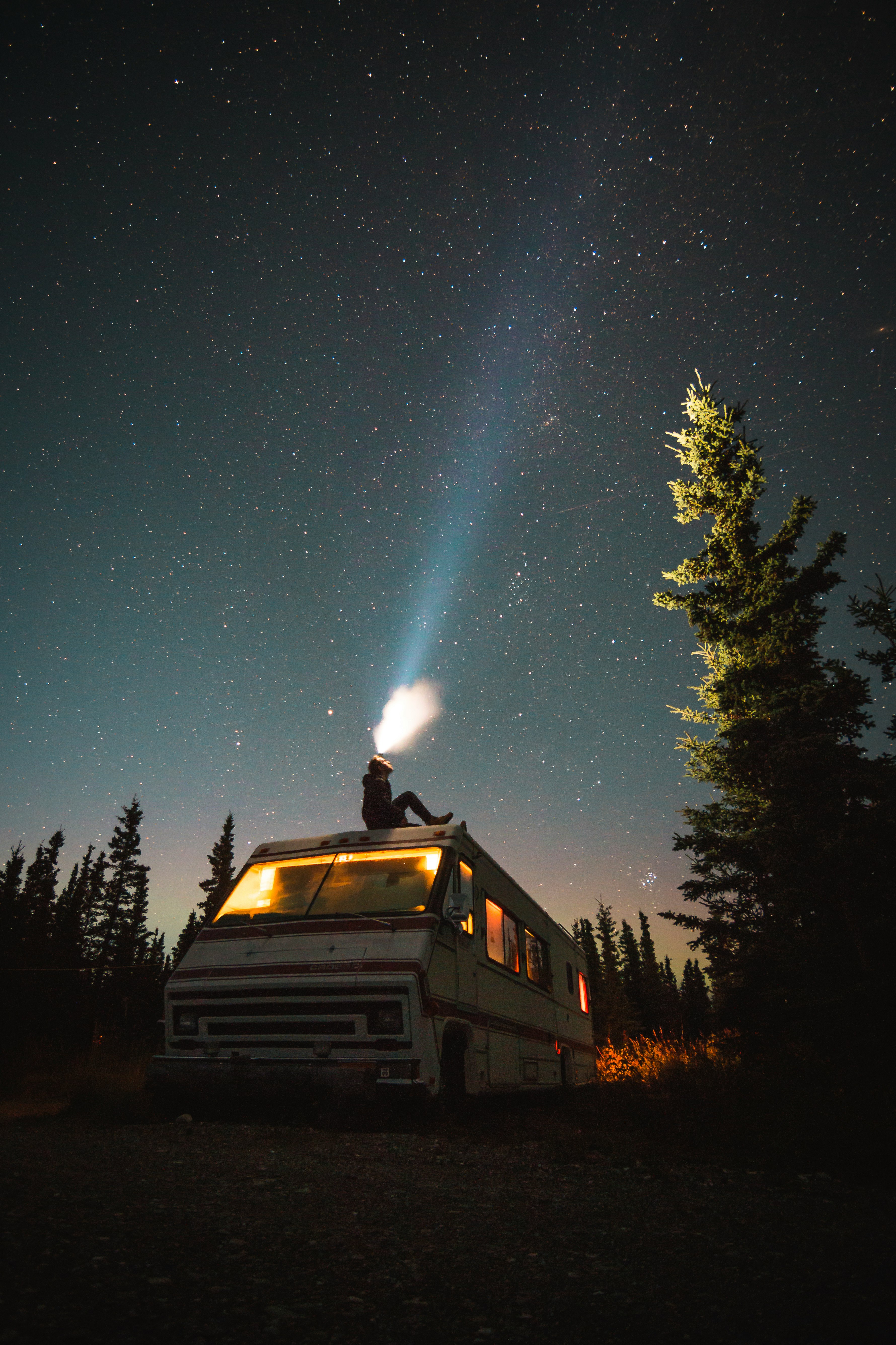 person sits on top of van at night
