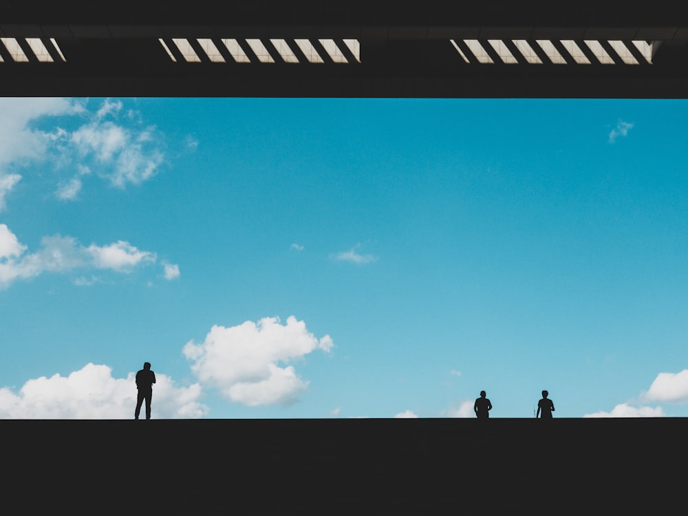 silhouette of three person against blue sky