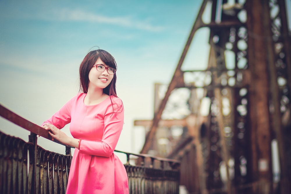 woman leaning on wooden handrail while facing to her left