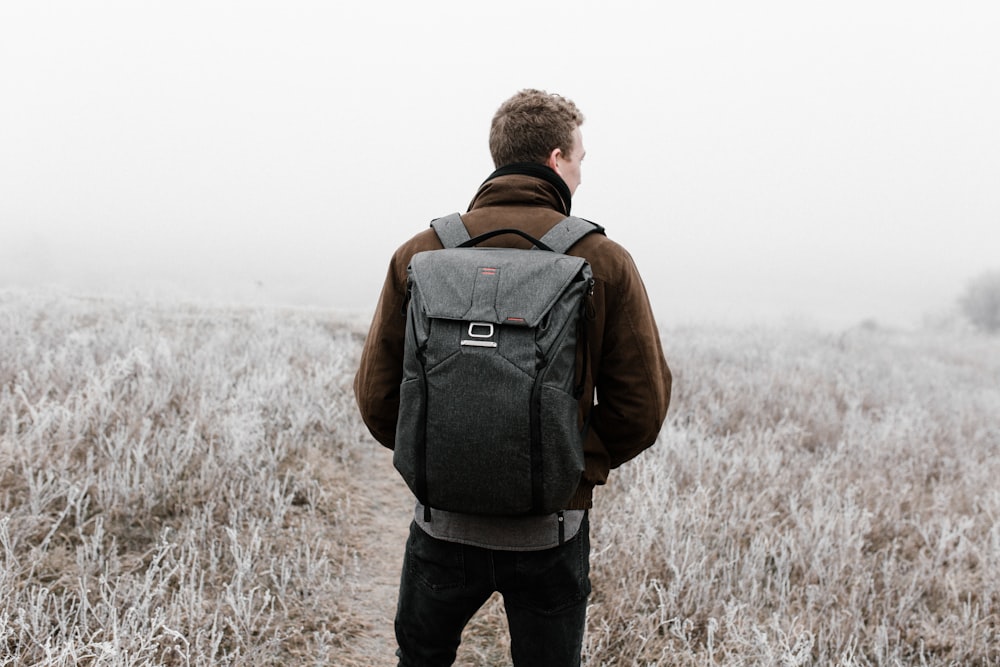 man wearing backpack walking on pathway