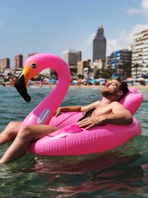 man lying on flamingo buoy suggesting good genetic screening
