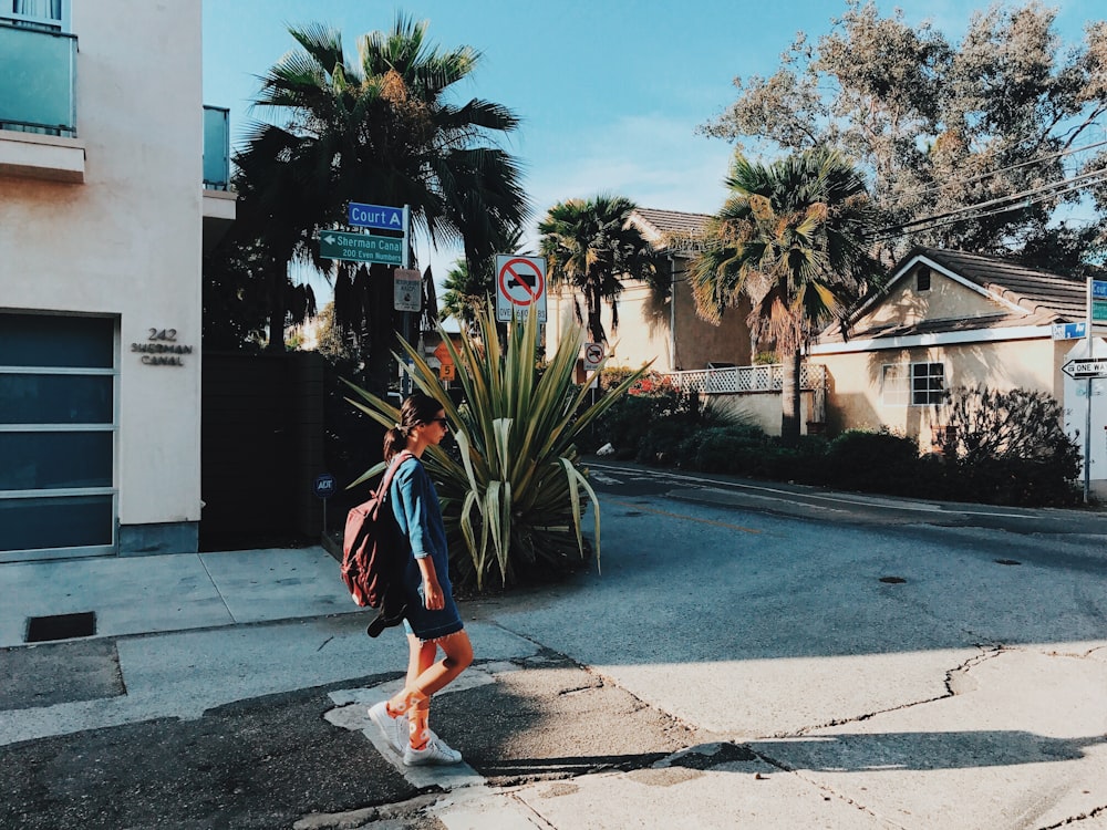 walking woman with backpack near house at daytime