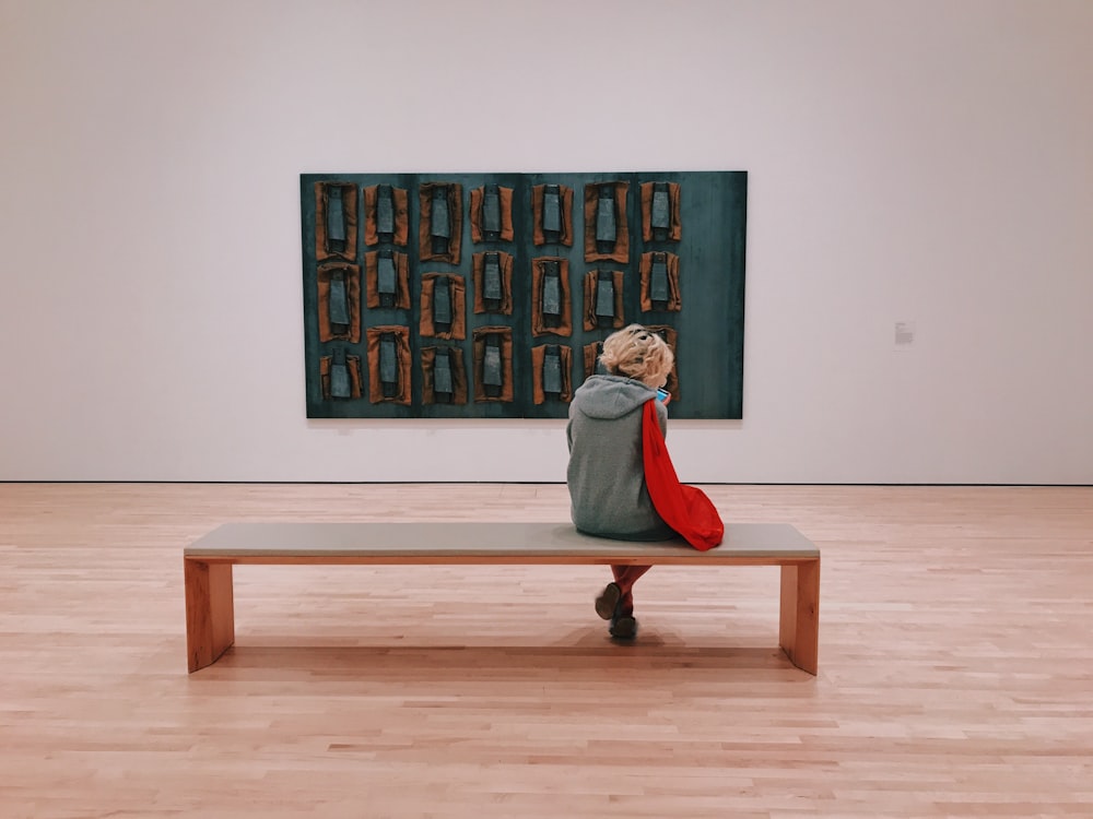 pessoa sentada no banco à frente da pintura