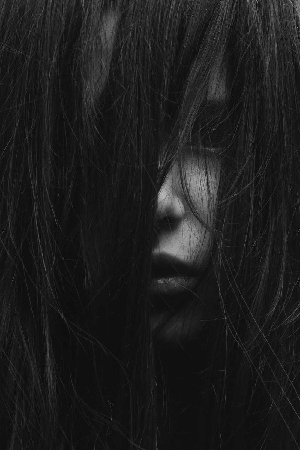 Graustufenfotografie eines Mädchens, das ihr Gesicht mit Haaren bedeckte