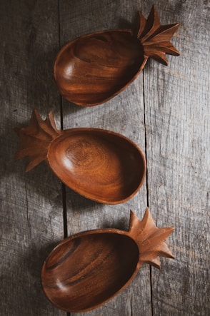 three brown wooden bowls on gray wood