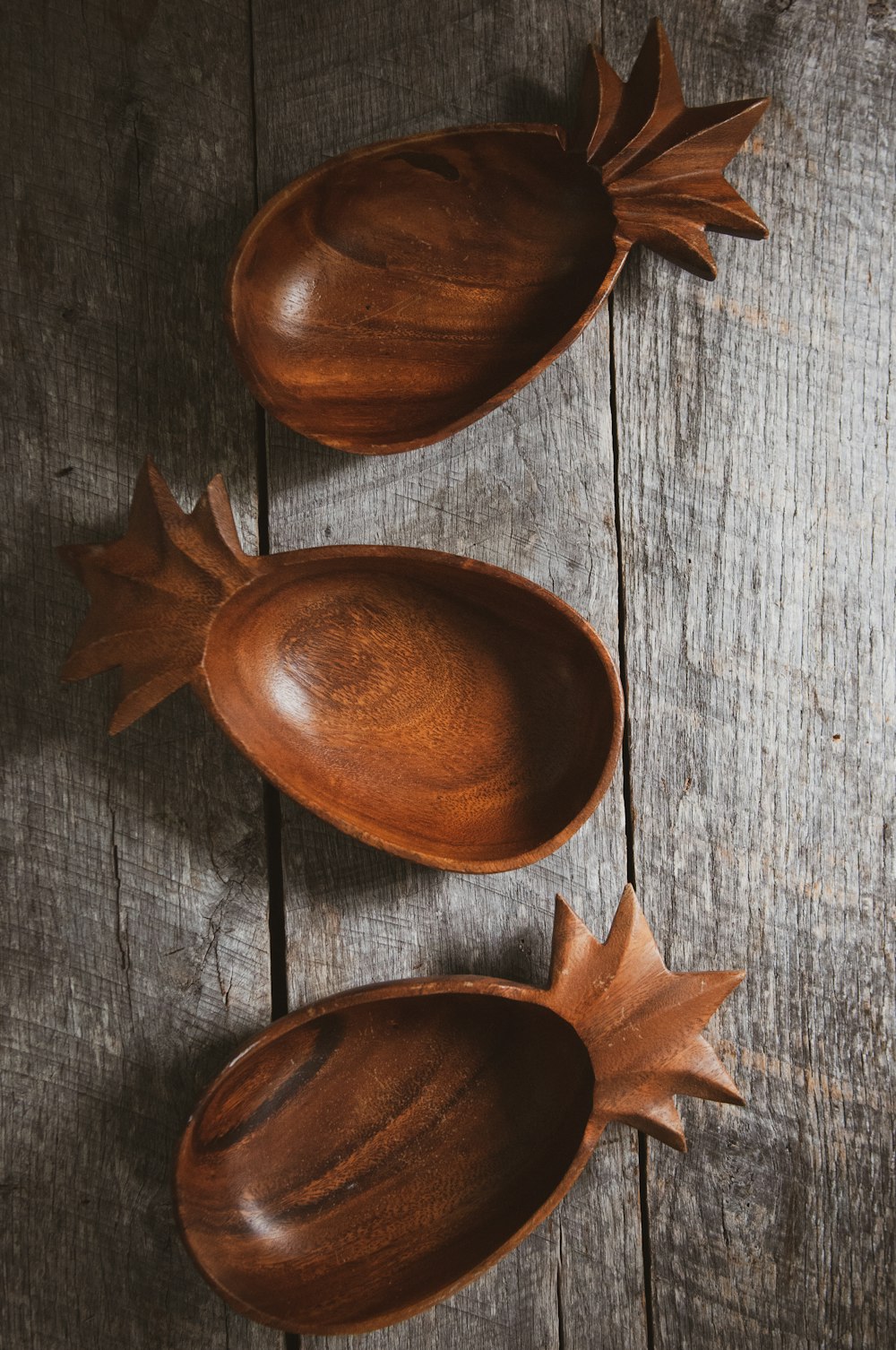three brown wooden bowls on gray wood