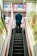 man in blue suit jacket standing on escalator