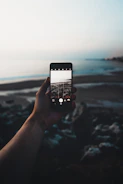 selective focus photography of person taking photo of seashore