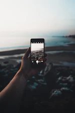 selective focus photography of person taking photo of seashore