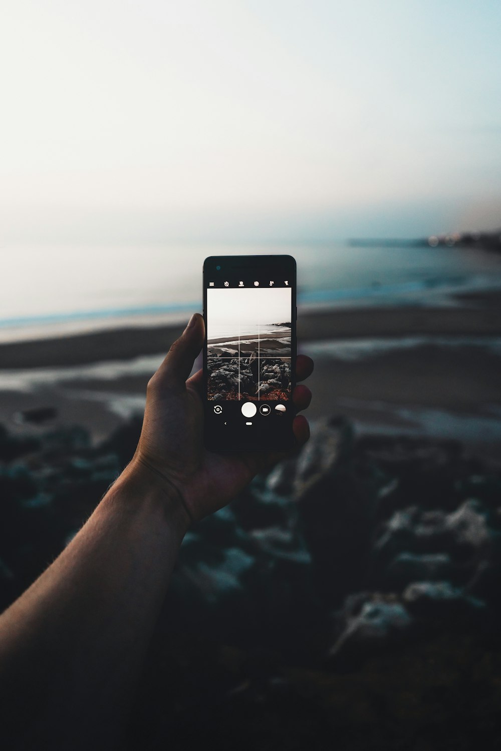 selective focus photography of person taking photo of seashore