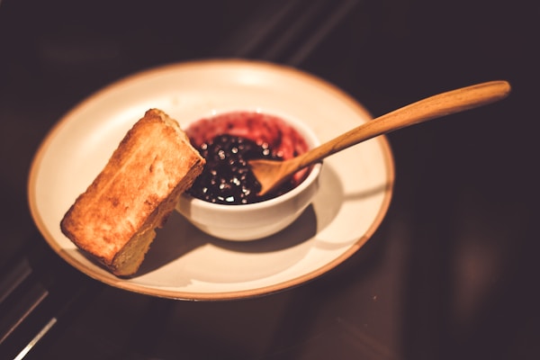 Blueberry jam in bowl with spoon and slice of bread