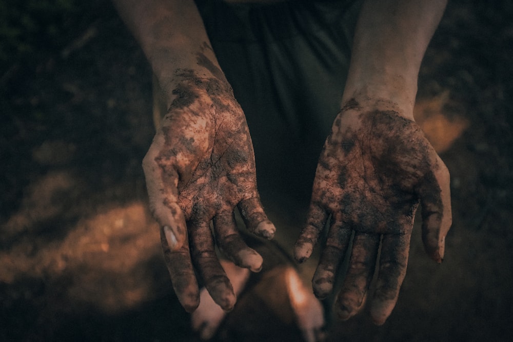 a person covered in mud holding out their hands
