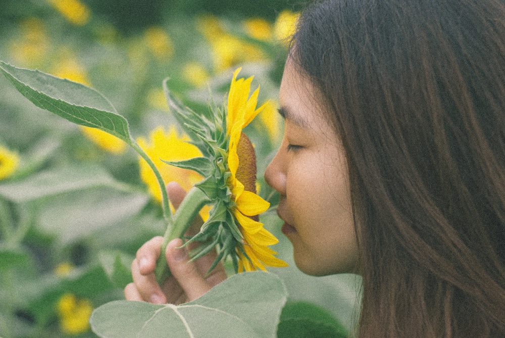 woman sniffing sunflower