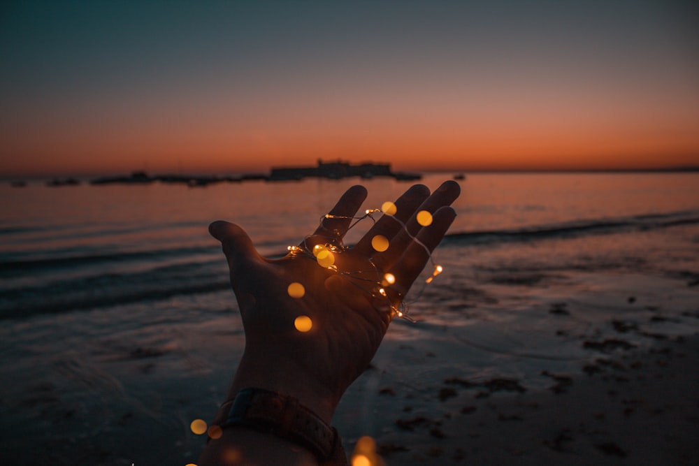 Persona con guirnaldas de luces en la mano izquierda