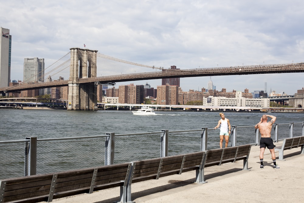 two men taking picture in front of Brooklyn Bridge