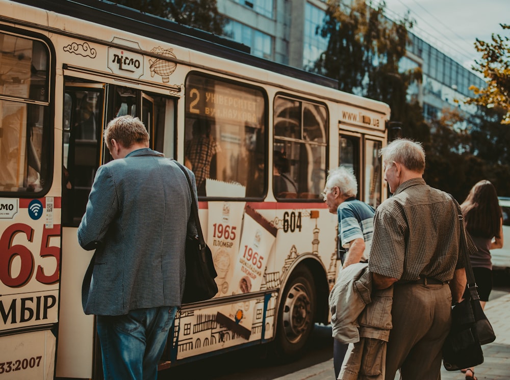 three men standing outside bus