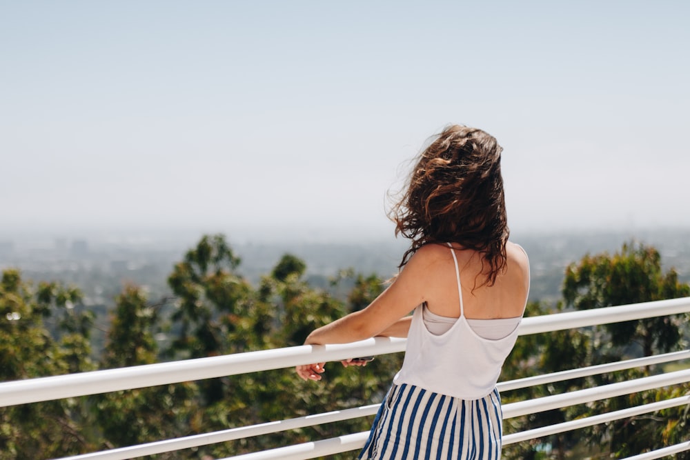 selective focus photography of woman standing beside rail during daytime