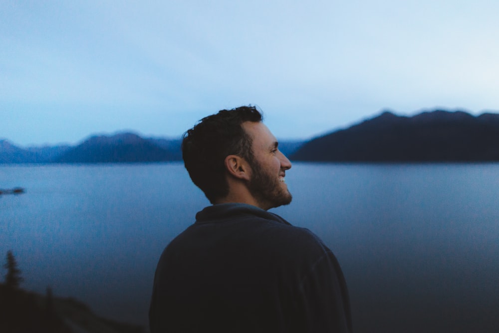 man standing beside body of water