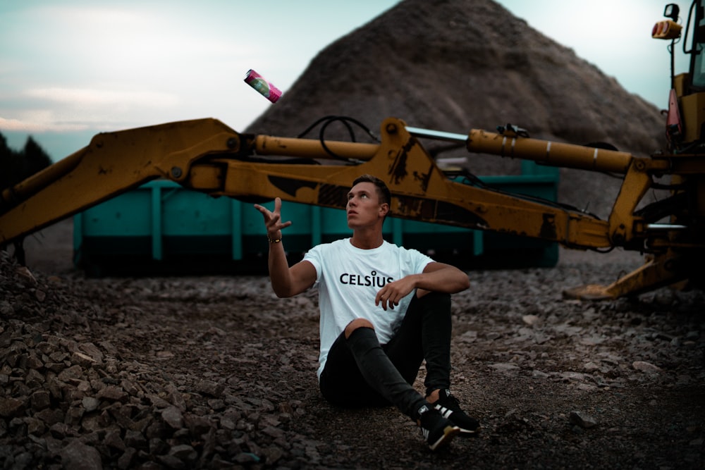 man sitting on the ground near excavator