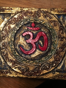 Elegant yantra engraved on a sandalwood plaque surrounded by soft maroon highlights.