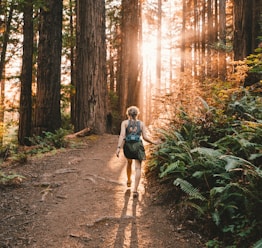 a woman walking down a path in the woods